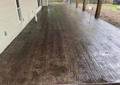 Stamped concrete patio with state of Texas outline imprinted over wooden deck pattern by JP Custom Concrete